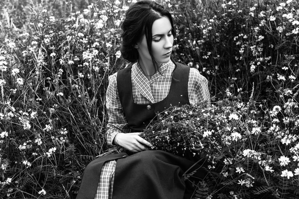 Outdoor portrait of a beautiful brunette woman in blue dress in the field. Black and white photo