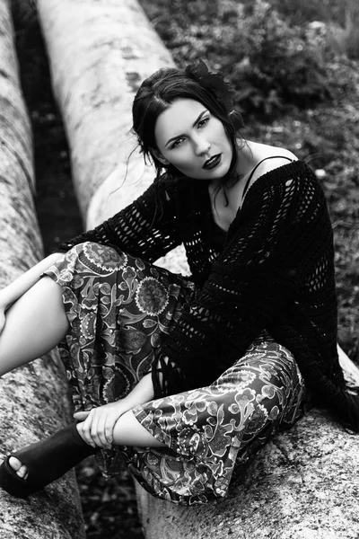 Fashion outdoor portrait of a beautiful brunette woman with flowers in hair in the field. Black and white photo