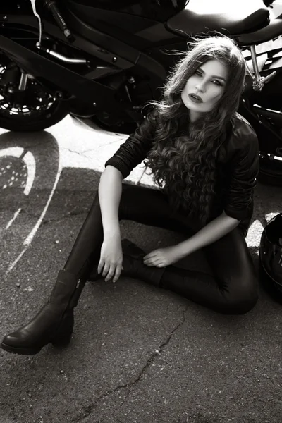 Sexual biker woman wearing black leather jacket with her sport motorcycle on a highway. Beauty, fashion. Adventure and freedom. Black and white photo