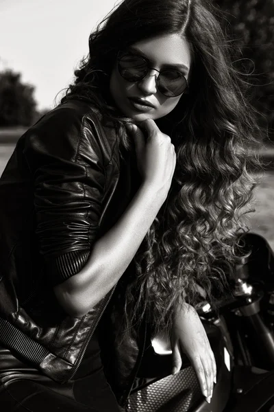 Sexual biker woman wearing black leather jacket with her sport motorcycle on a highway. Beauty, fashion. Adventure and freedom. Black and white photo