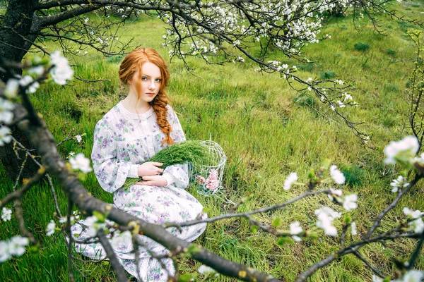 Portrait of a beautiful redhead girl in the spring garden