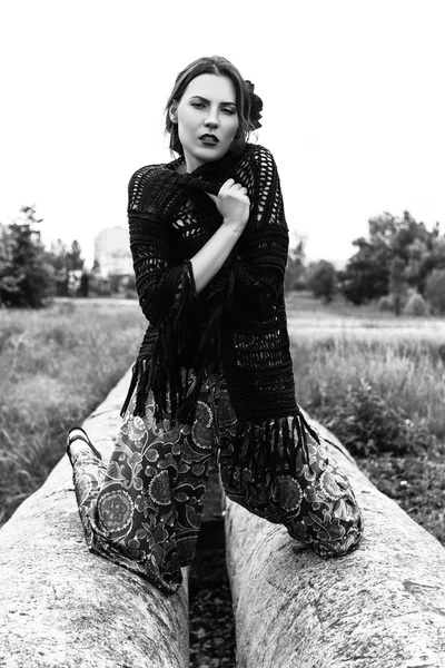 Fashion outdoor portrait of a beautiful brunette woman with flowers in hair in the field. Black and white photo