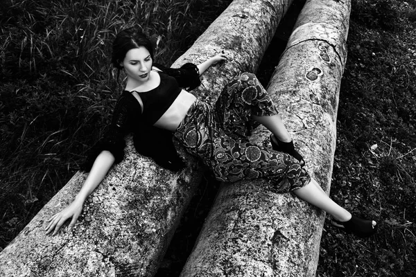 Fashion outdoor portrait of a beautiful brunette woman with flowers in hair in the field. Black and white photo