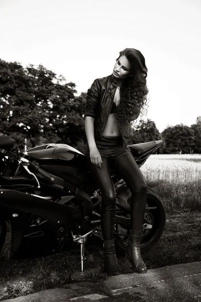 Sexual biker woman wearing black leather jacket with her sport m