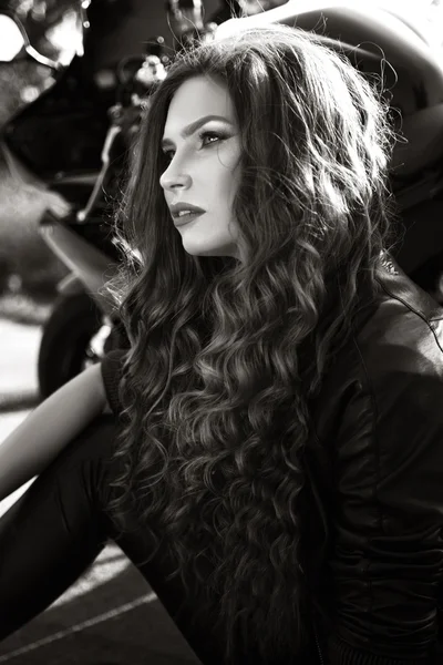 Sexual biker woman wearing black leather jacket with her sport motorcycle on a highway. Beauty, fashion. Adventure and freedom. Black and white photo