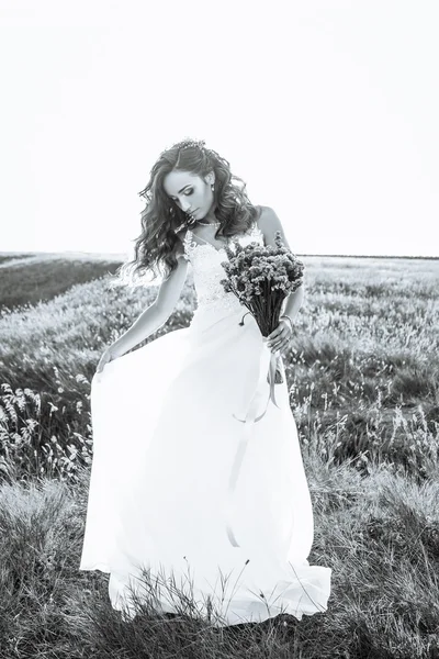 Young woman in wedding dress outdoors. beautiful bride in a field at sunset. Black and white