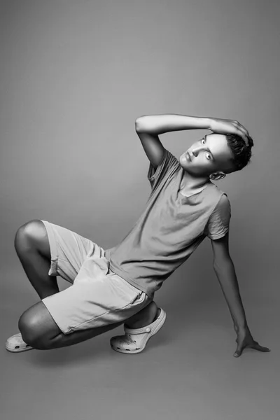 Vertical portrait of young man in casual clothes sitting in studio. Black and white