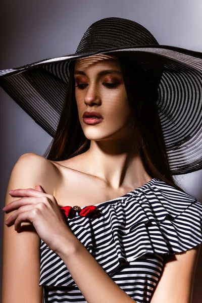 Fashion girl in a big hat in the studio