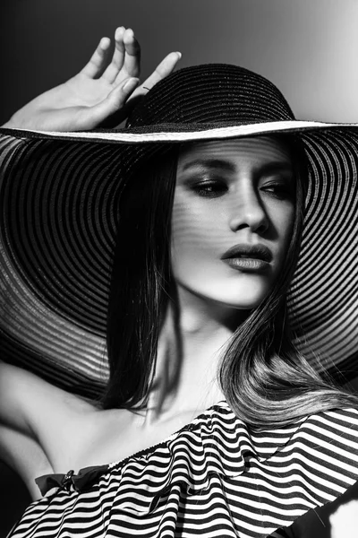 Fashion girl in a big hat in the studio. Black and white