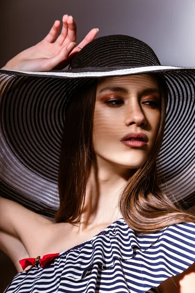 Fashion girl in a big hat in the studio