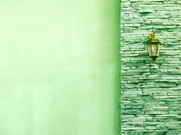 Lamp in middle light green ancient stone pieces wall at right an