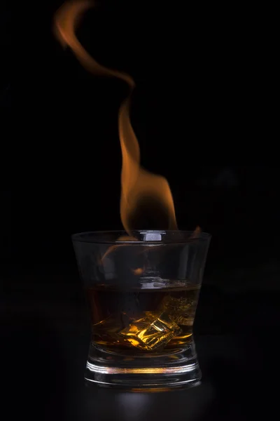 The concept of hot drink with ice cubes in a glass. On a black b