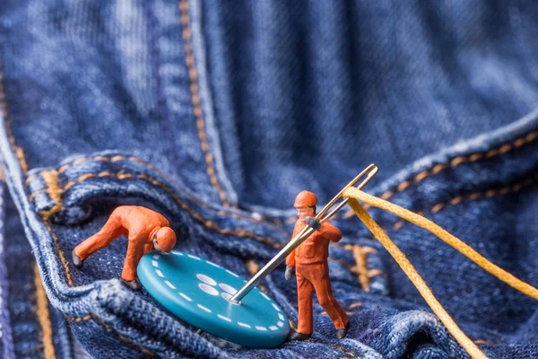 The concept for the fashion industry. Miniature workers sew on b