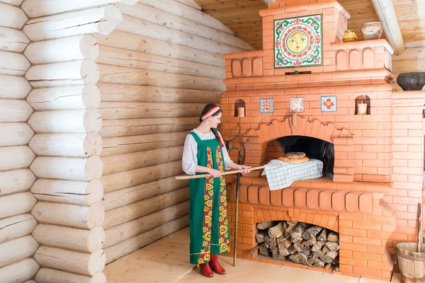 Woman bakes bread in a Russian stove