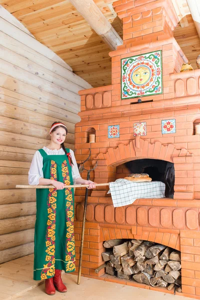 Woman bakes bread in a Russian stove