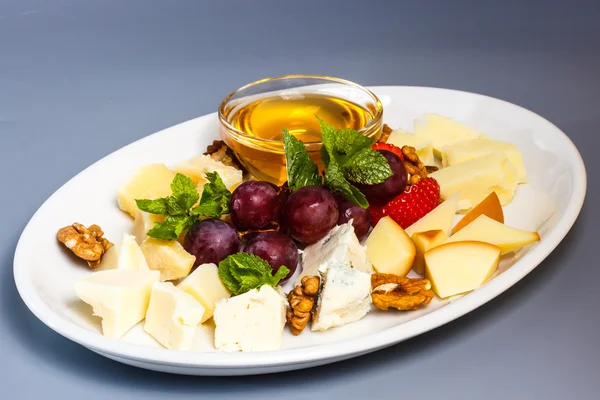 A plate of different cheeses and berries.