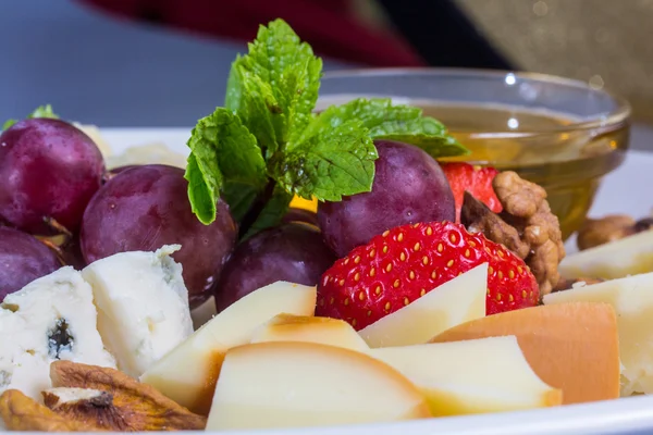 A plate of different cheeses and berries.