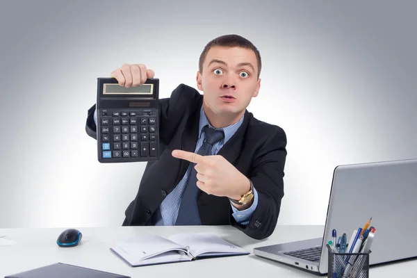 Very angry businessman in office, holding a calculator