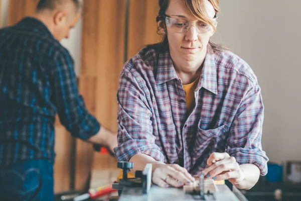 Woman working at carpenter shop with teacher