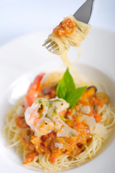 Shrimp spaghetti with tomato sauce on a fork.