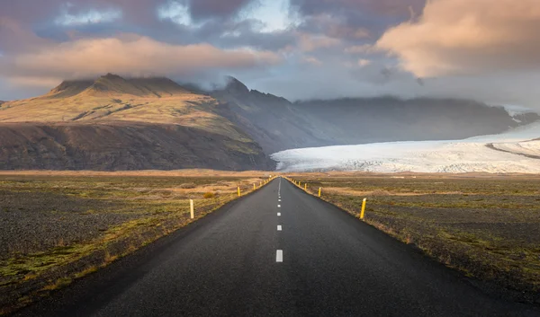 Road line perspective with glacier and mountain range background during sunset time in Autumn season at Iceland