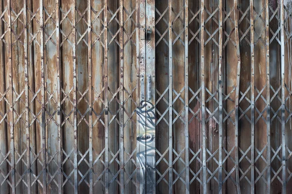 Asian rusty folding doors or traditional gate. Old steel rusty door texture pattern. Folding door texture pattern and background with graffiti on handle.
