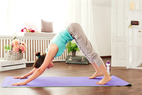 Young caucasian woman staying in a pose on the mat downward dog. Yoga exercises.