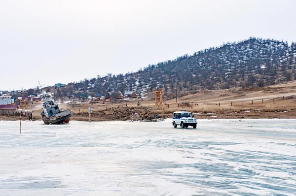 Ice ferry to Olkhon. Police car and boat on the shore