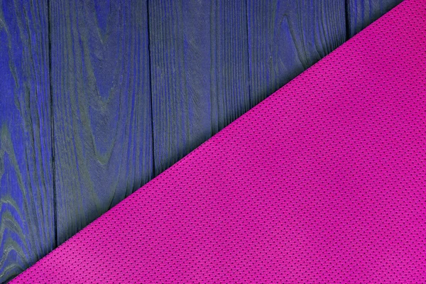 Detail of perforated pink yoga mats on the wooden background. Texture yoga mats and boards. Boards blue. The diagonal orientation. The concept of a healthy lifestyle. Weight loss and fitness.
