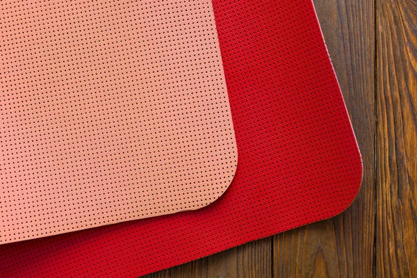 New yoga mat of red and pink flowers on wooden background.