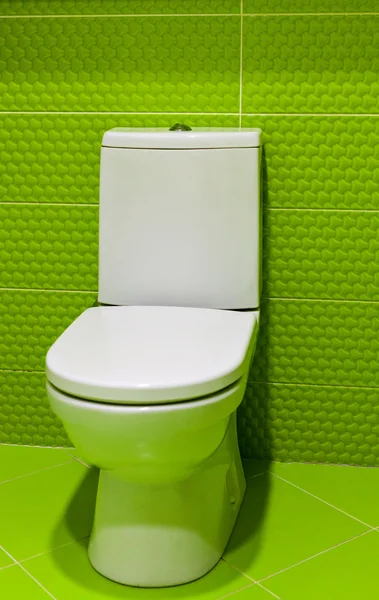 Clean, white toilet  with Lime green mosaic