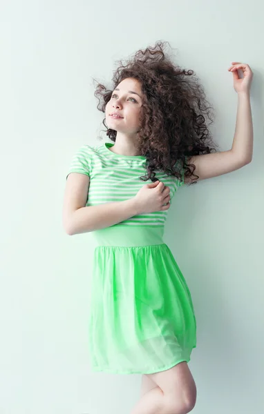 A young girl of Caucasian appearance dancing and dreams of a bright room on a summer day. Wavy curly hair and green dress. Rest and be happy.