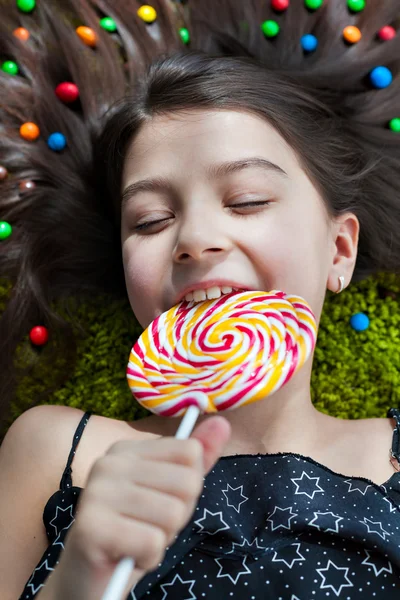 Little girl lying on the floor with his eyes closed and eating candy