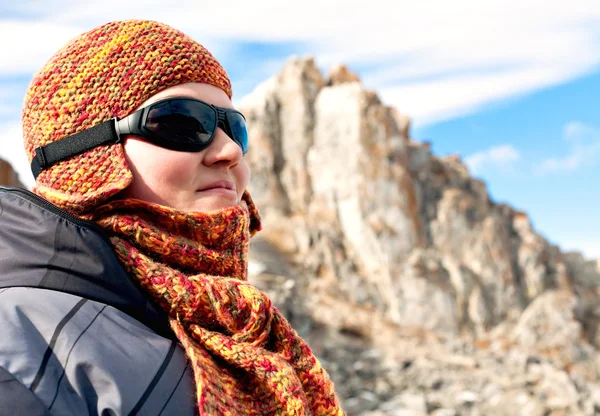 Portrait of a girl in orange scarves and hats against the blue s