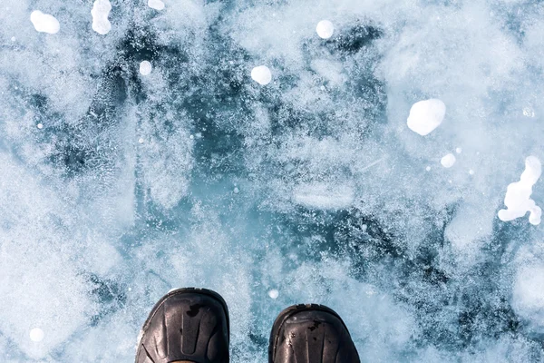 Human foot in shoes on the ice of Lake Baikal.