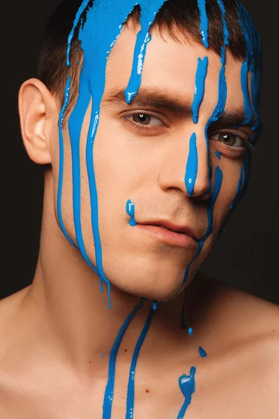 Portrait of young handsome male model with paint on his face