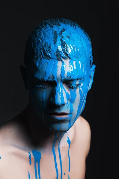 Close-up portrait of young handsome male model with paint on his face. Portrait with eyes closed