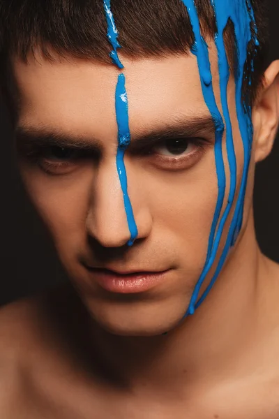 Close-up portrait of young handsome male model with paint on his face