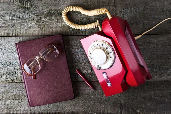 Vintage red phone, old glasses and notebook