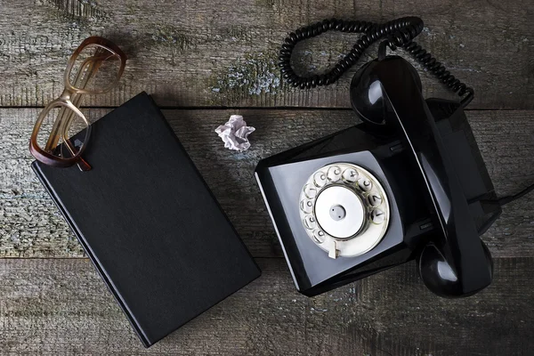 Vintage black phone, old glasses and notebook