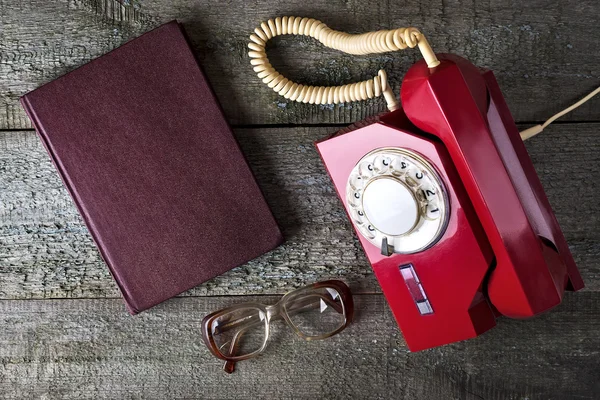 Vintage red phone, old glasses and notebook