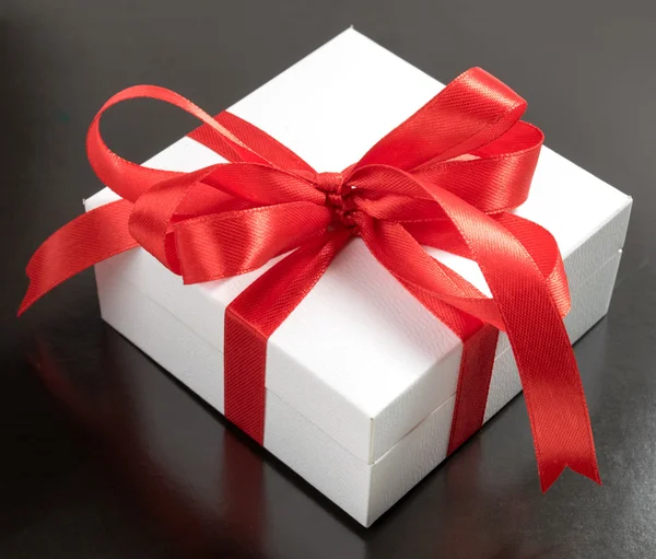 White gift box with red ribbons isolated on black background