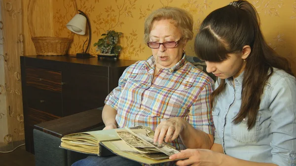 Old and young woman looking at family photo album
