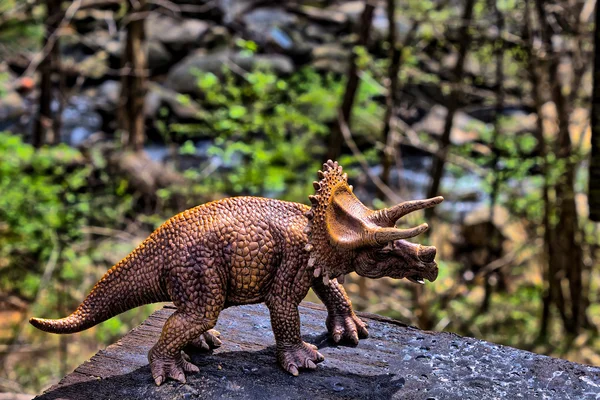 Brown Triceratops dinosaur  with woods in the background