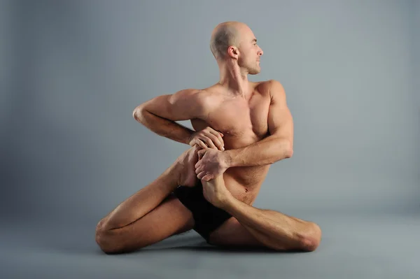 Yoga man posing on a gray background