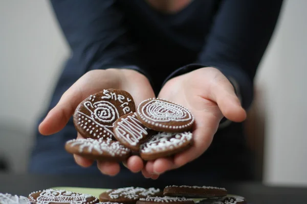 Girl offering cookies (gingerbread) that she holds in her hands.