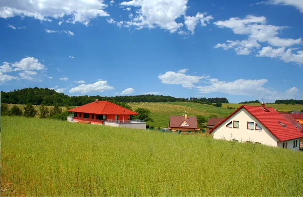 Family houses in satellite town over the green hilly field with blue sky with few clouds