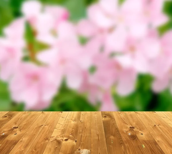 Wooden style floor and blurred pink flower for display of produc
