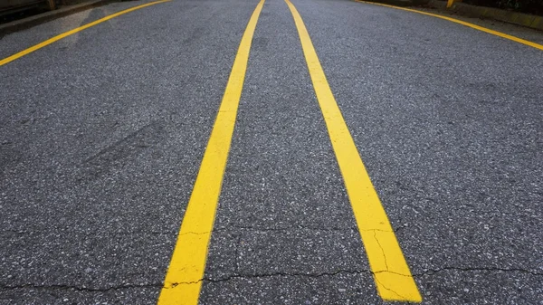 Yellow line on street divided between car at parking lot of load