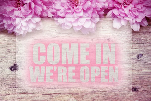 Pink flowers on wooden with word Come in we\'re open